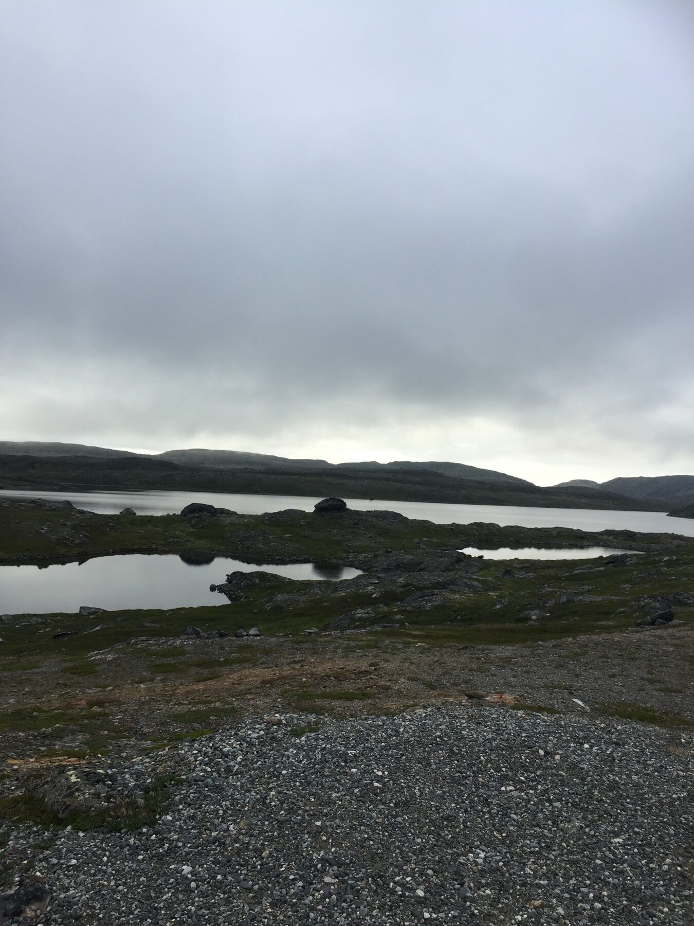 Dempet fjellandskap med stille vann under lavt skydekke