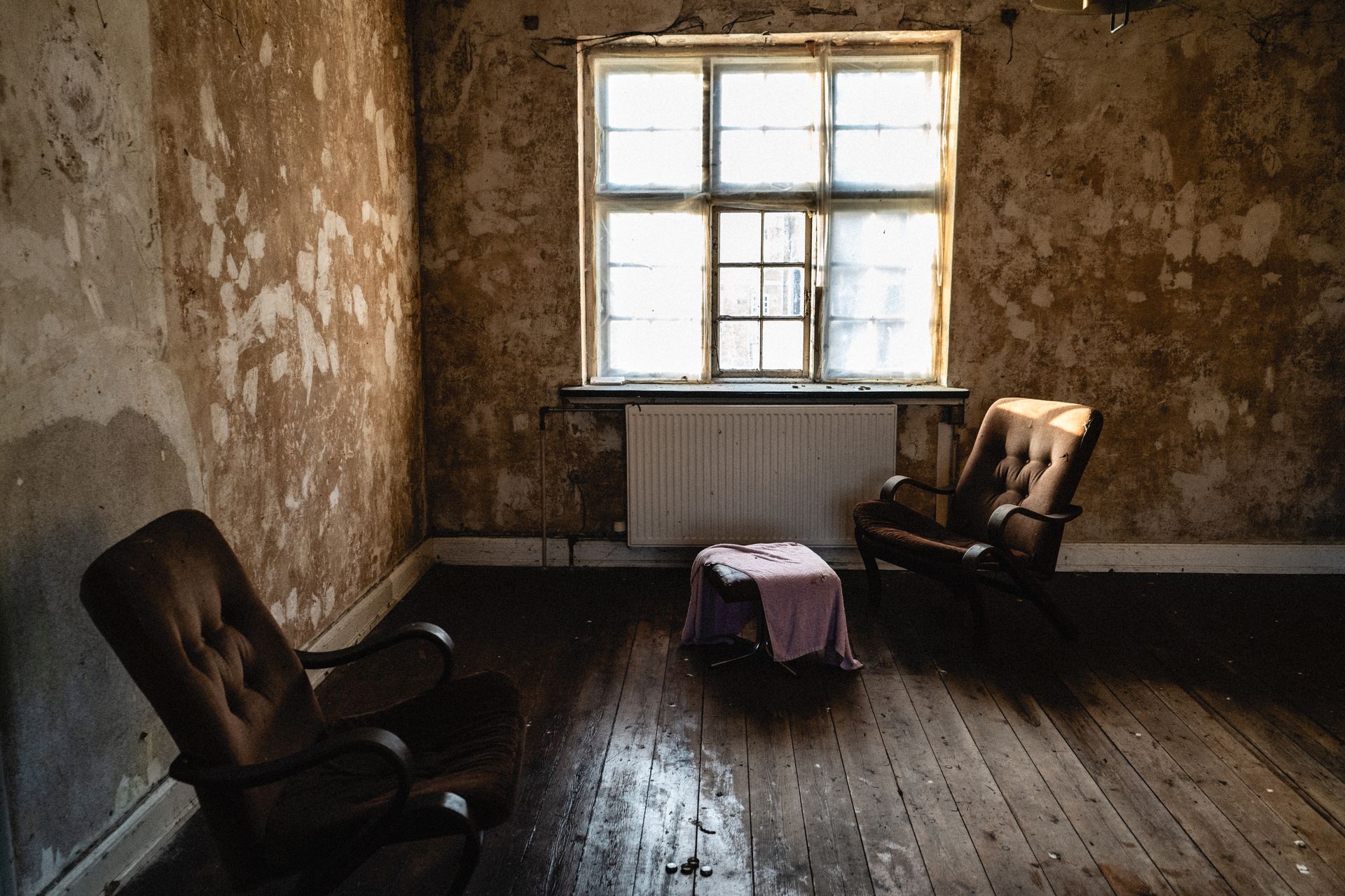 To tomme lenestoler i et stille rom med dagslys fra vinduet